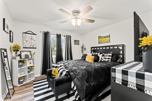 bedroom with light wood-type flooring, a ceiling fan, and baseboards