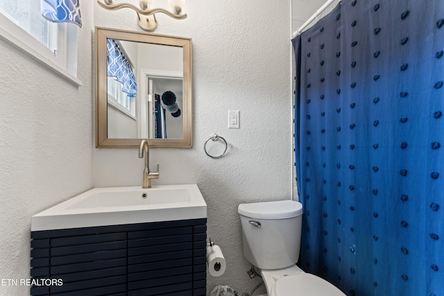 full bath with a textured wall, vanity, a shower with shower curtain, and toilet