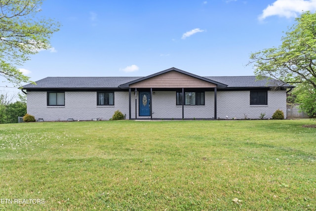 ranch-style home featuring brick siding, a front yard, and roof with shingles