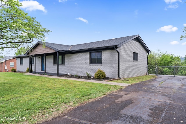 single story home with brick siding, a front yard, aphalt driveway, and fence