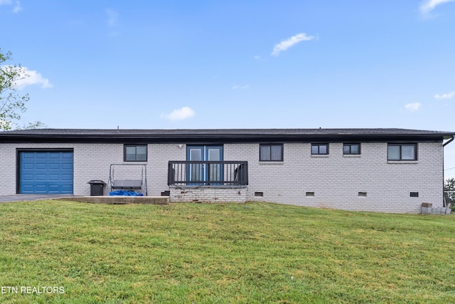 rear view of property featuring driveway, a garage, brick siding, a lawn, and crawl space