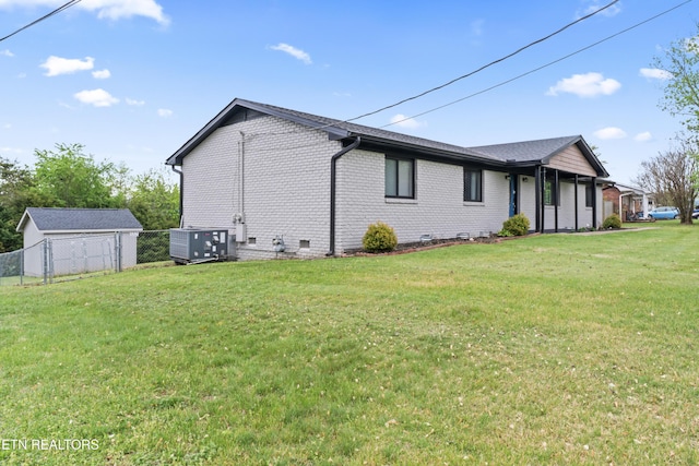 view of property exterior featuring brick siding, central AC unit, fence, and a yard