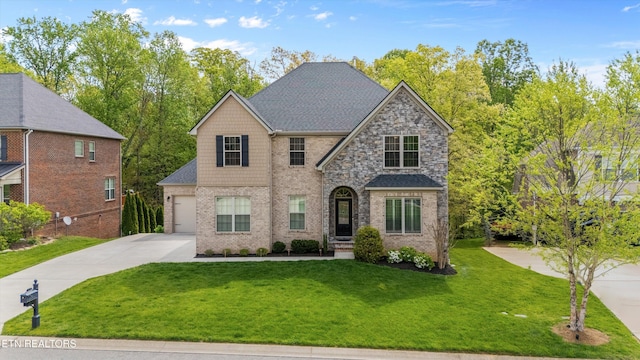 view of front of property featuring a front lawn, a garage, brick siding, driveway, and roof with shingles