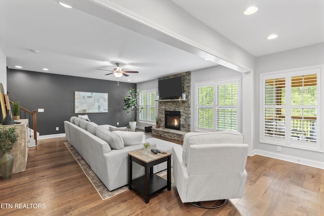 living room featuring wood-type flooring, a ceiling fan, baseboards, and a fireplace