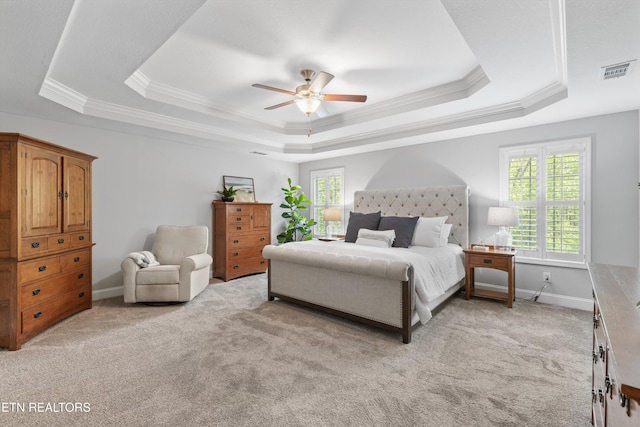 bedroom with crown molding, visible vents, light carpet, and a tray ceiling