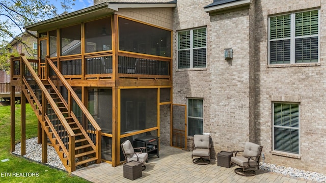 back of house with a sunroom, stairs, brick siding, and a patio area