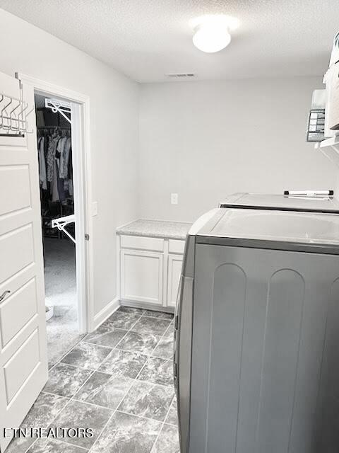 laundry area with visible vents, cabinet space, a textured ceiling, and washing machine and dryer