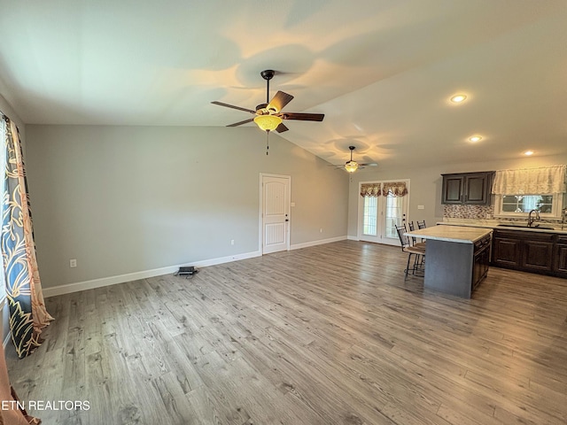 unfurnished living room with a ceiling fan, a sink, wood finished floors, and baseboards