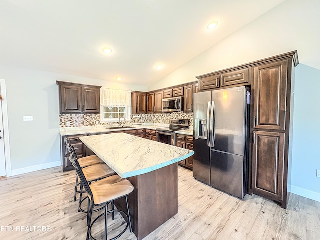 kitchen featuring appliances with stainless steel finishes, tasteful backsplash, lofted ceiling, and a sink