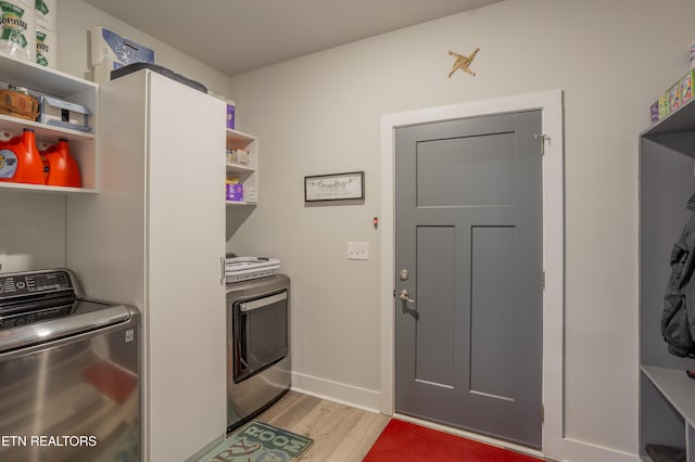 laundry area with washing machine and dryer, light wood-style floors, baseboards, and laundry area