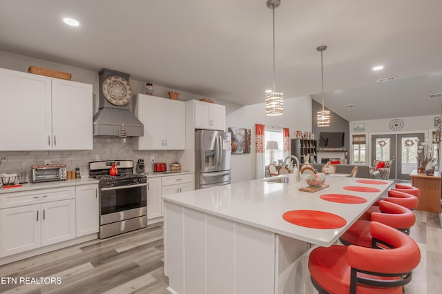 kitchen featuring open floor plan, white cabinetry, backsplash, light countertops, and appliances with stainless steel finishes