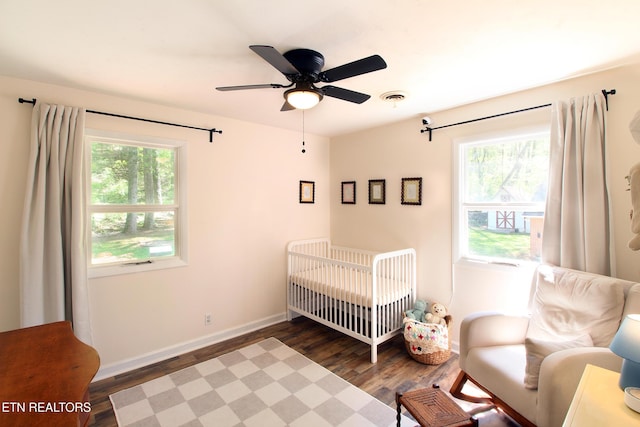 bedroom with baseboards, wood finished floors, multiple windows, and visible vents