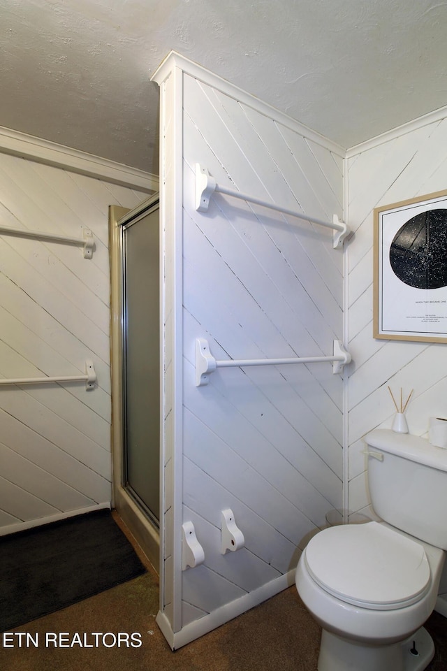 bathroom with a shower stall, toilet, and wooden walls
