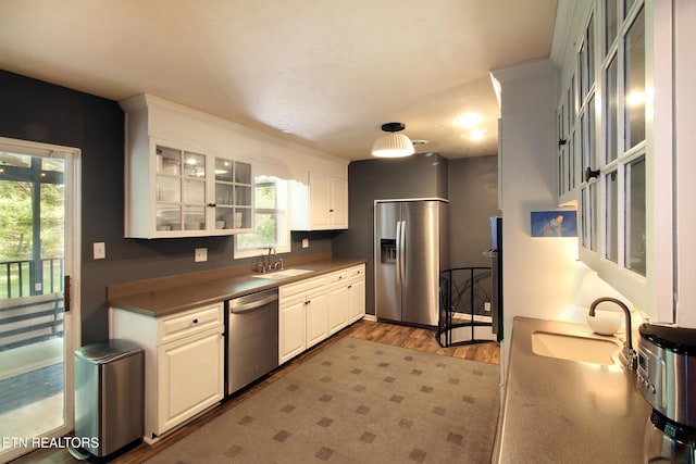 kitchen with wood finished floors, white cabinetry, stainless steel appliances, and a sink
