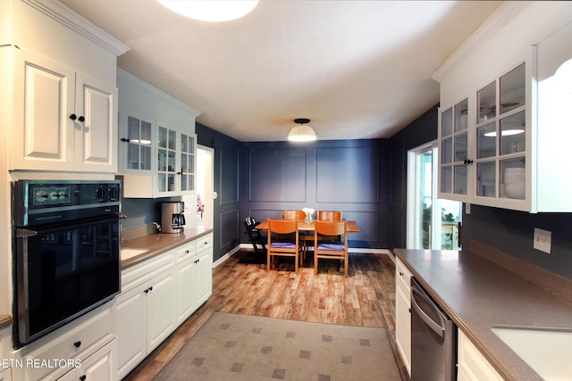 kitchen featuring oven, light wood-type flooring, white cabinetry, glass insert cabinets, and dishwasher