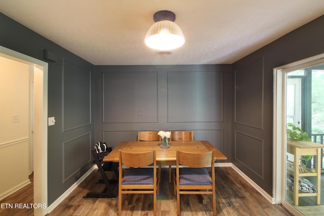 dining space with dark wood-type flooring and a decorative wall