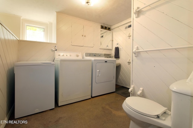 laundry room featuring wooden walls, visible vents, washer and clothes dryer, and laundry area