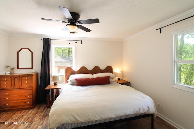 bedroom with ceiling fan, crown molding, wood finished floors, and multiple windows
