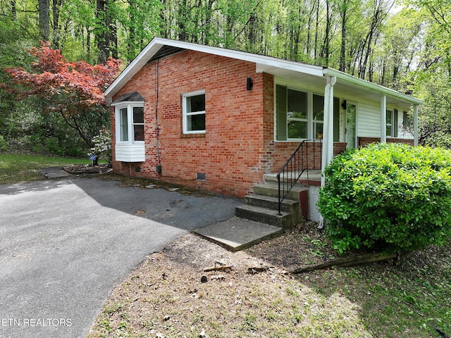view of front of house with brick siding and crawl space