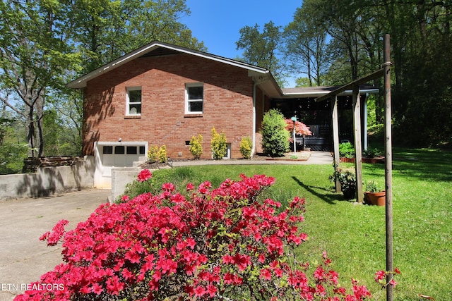 view of side of home featuring an attached garage, brick siding, a yard, and concrete driveway