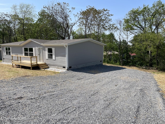 view of front of home featuring a wooden deck, crawl space, and gravel driveway