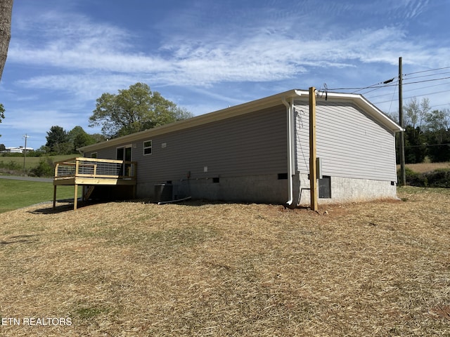 view of property exterior featuring crawl space, central AC, and a deck