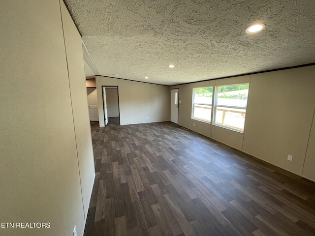 empty room featuring dark wood-type flooring, a textured ceiling, baseboards, and recessed lighting