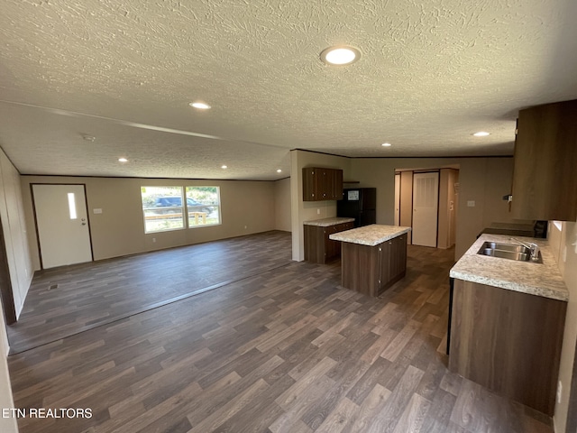 kitchen with a center island, a textured ceiling, open floor plan, dark wood-type flooring, and freestanding refrigerator
