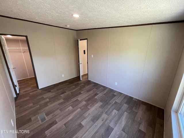 unfurnished bedroom with a textured ceiling, a decorative wall, and crown molding