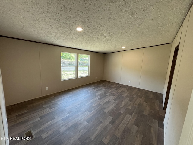 spare room featuring a decorative wall, a textured ceiling, recessed lighting, and dark wood finished floors