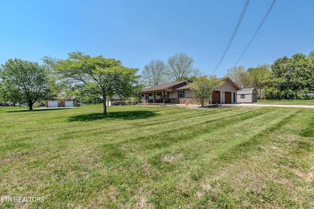 view of yard featuring driveway, a porch, and a garage