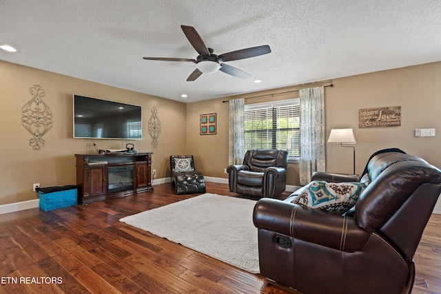 living room featuring a textured ceiling, ceiling fan, and wood finished floors