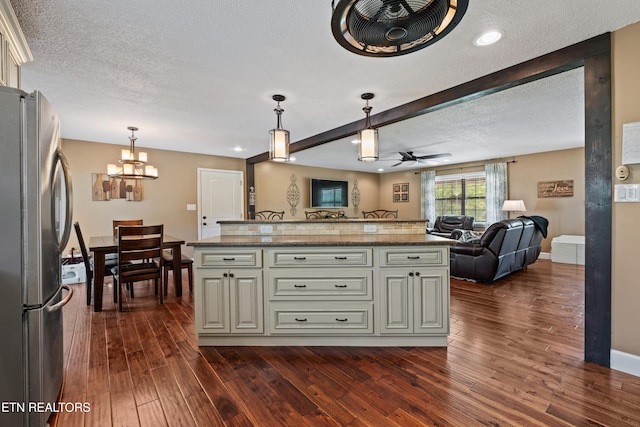 kitchen with open floor plan, dark wood finished floors, freestanding refrigerator, and a textured ceiling