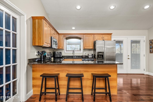 kitchen featuring dark wood finished floors, stainless steel appliances, french doors, a sink, and a peninsula