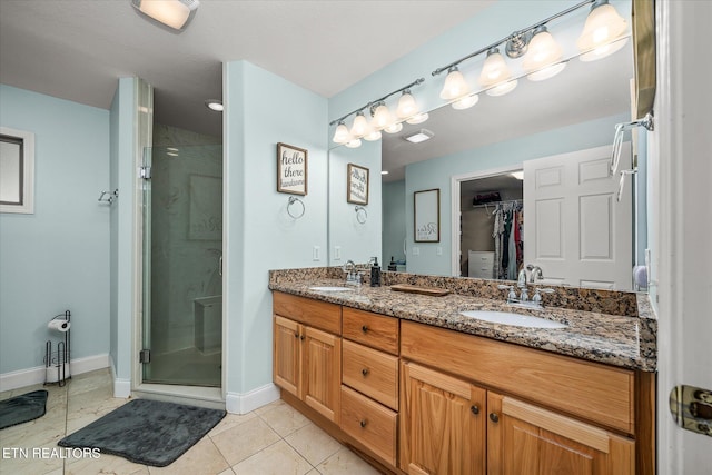 bathroom with a sink, a stall shower, a spacious closet, double vanity, and baseboards