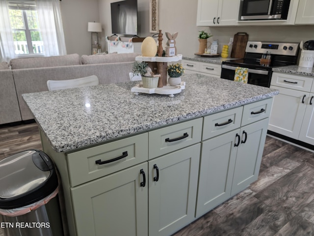 kitchen featuring light stone countertops, open floor plan, a center island, and appliances with stainless steel finishes