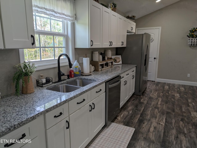 kitchen featuring white cabinets, stainless steel appliances, a sink, lofted ceiling, and light stone countertops
