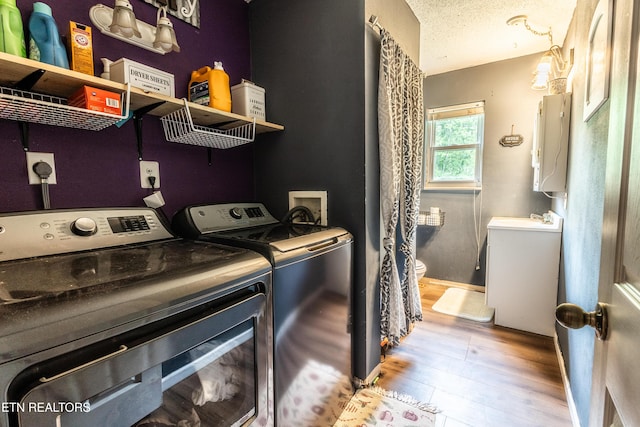 clothes washing area with a sink, laundry area, wood finished floors, and washer and dryer