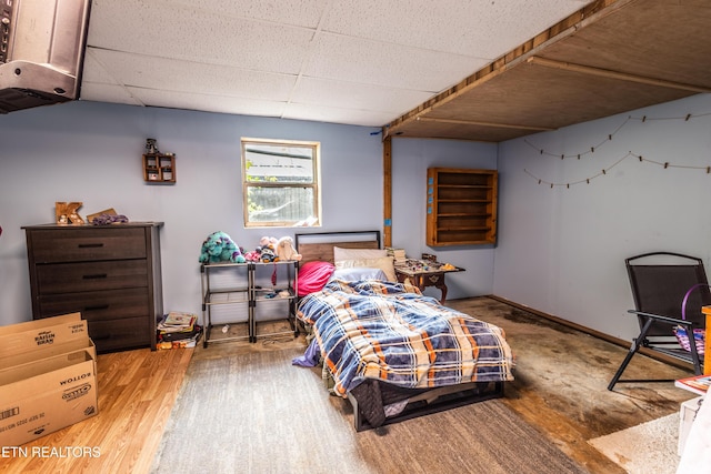 bedroom with a drop ceiling and wood finished floors