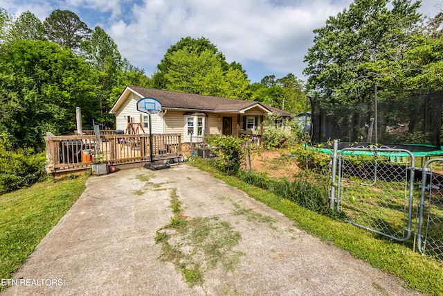 view of front of house with a trampoline, a front lawn, driveway, and a deck