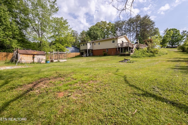 view of yard with fence, a wooden deck, and an outbuilding