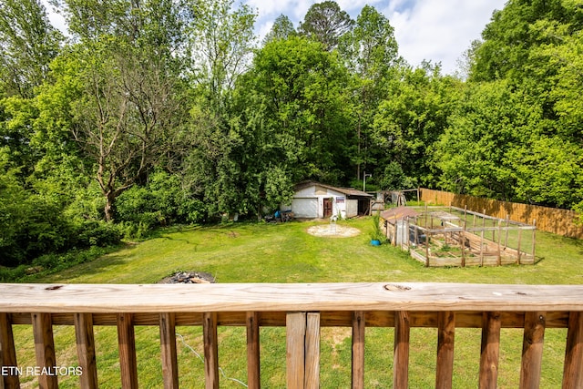view of yard featuring an outdoor structure, fence, and a vegetable garden