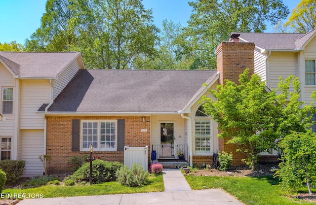 view of front of home featuring a chimney, brick siding, and a shingled roof
