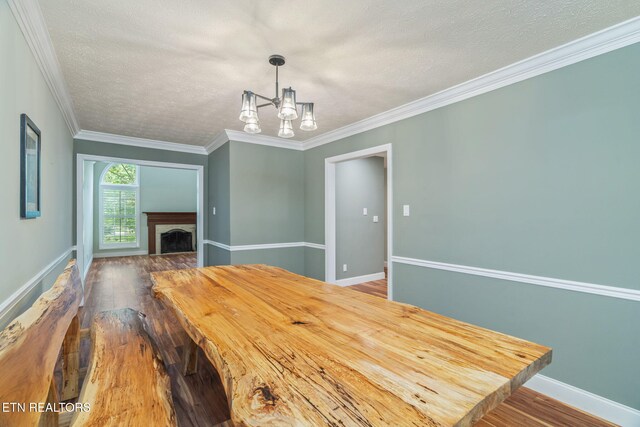 1109 Greywood Dr, Knoxville, TN 37923 - unfurnished dining area with wood-type flooring, a chandelier, ornamental molding, baseboards, and a textured ceiling