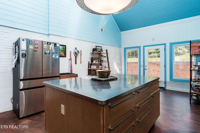 kitchen featuring freestanding refrigerator, a kitchen island, stainless steel counters, dark wood-style floors, and high vaulted ceiling