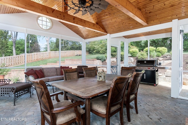sunroom with a healthy amount of sunlight, outdoor dining space, beamed ceiling, and ceiling fan