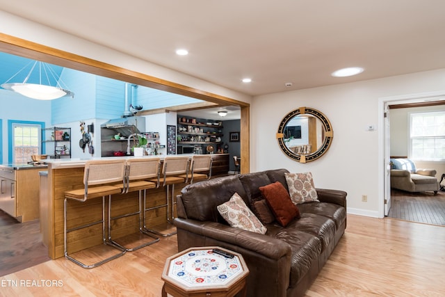 living room featuring light wood-type flooring, recessed lighting, a bar, and baseboards