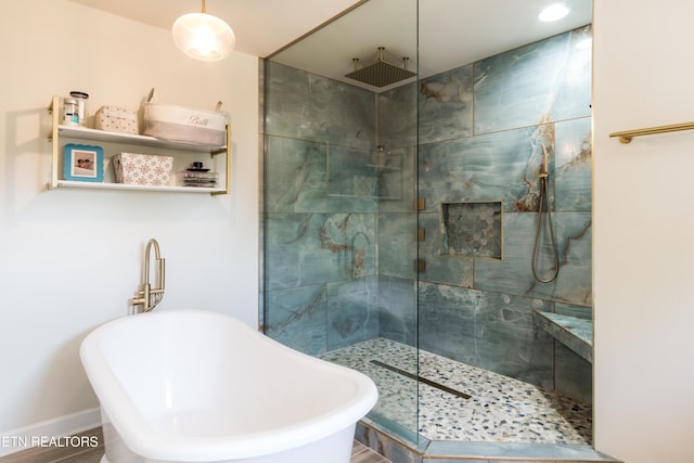 bathroom featuring a walk in shower, a sink, a freestanding tub, and baseboards