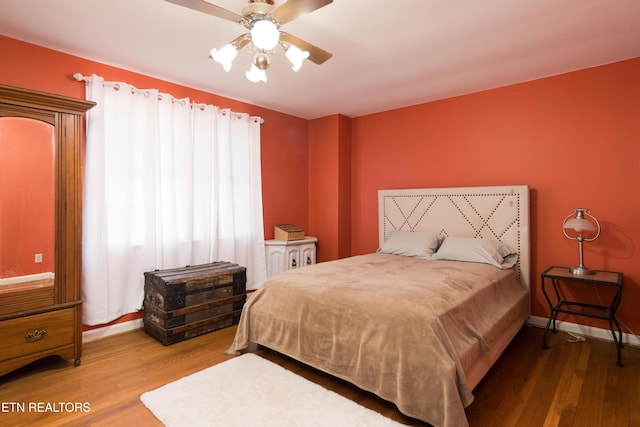 bedroom with a ceiling fan, wood finished floors, and baseboards