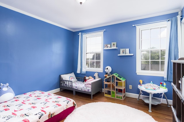 bedroom featuring baseboards, wood finished floors, and crown molding
